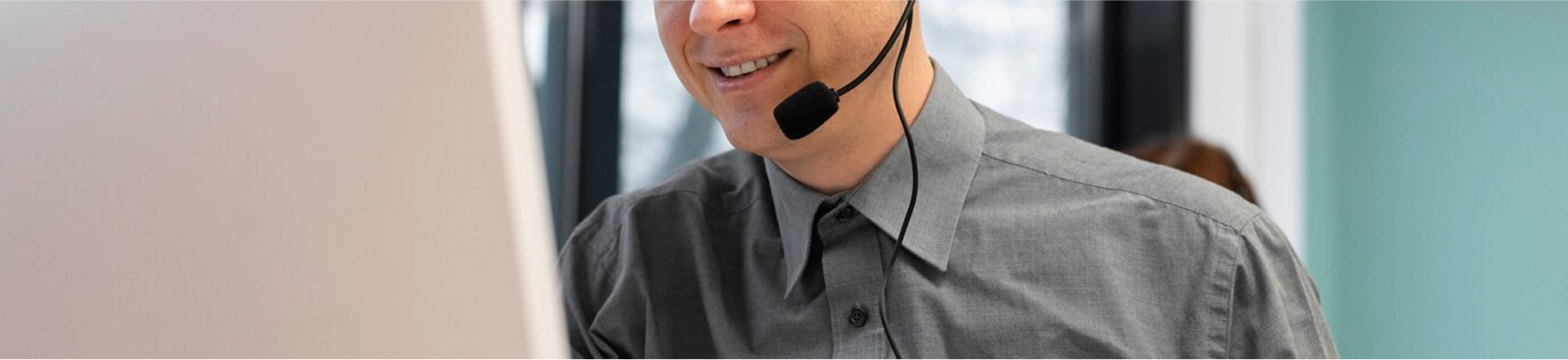 Man wearing a headset and smiling in front of a computer screen