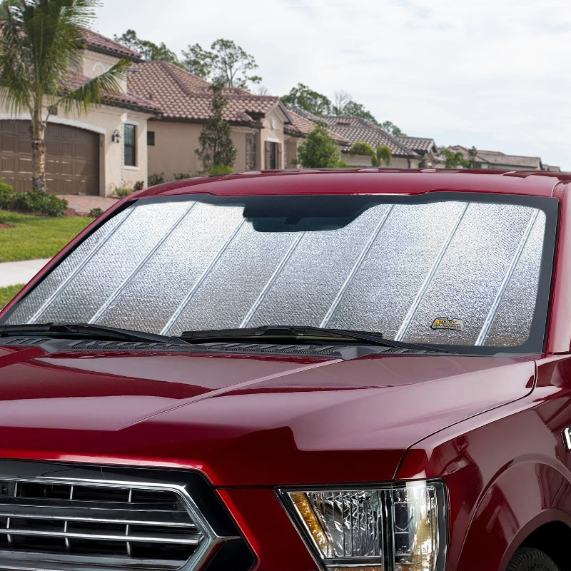Pickup windshield with an Ultimate Reflector sunshade covering it, parked outdoors.